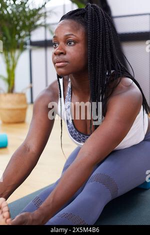La donna si allunga a materassino yoga Foto Stock