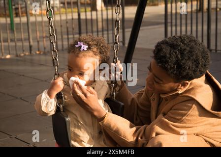 Madre che aiuta la figlia a soffiare il naso Foto Stock