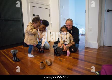 Genitori e figlie che si mettono le scarpe Foto Stock