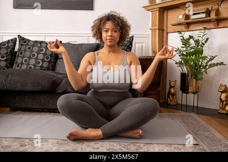 Donna meditando in salotto Foto Stock