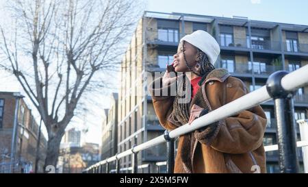 Giovane donna che parla con uno smartphone sul ponte Foto Stock