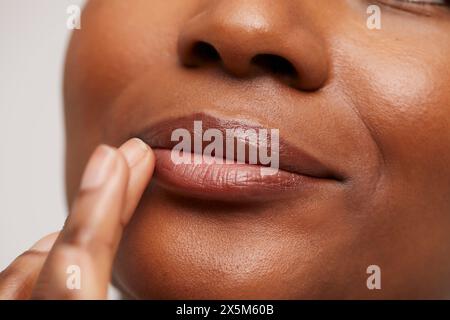Primo piano di una donna che tocca le labbra Foto Stock