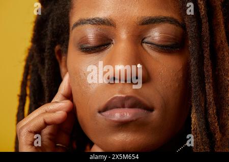 Primo piano di una donna con dreadlock e anello per il naso con gli occhi chiusi Foto Stock