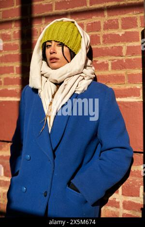 USA, New York City, donna con cappotto blu contro il muro di mattoni Foto Stock