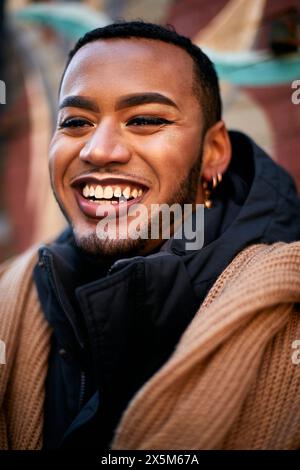 Ritratto di un uomo queer sorridente in giacca e sciarpa Foto Stock