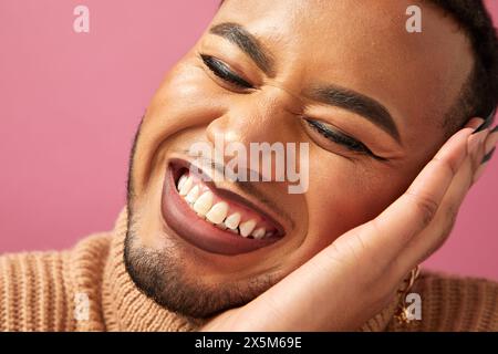 Primo piano di un uomo queer sorridente su sfondo viola Foto Stock