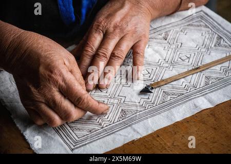 Una donna Flower Hmong disegna un modello per il suo ricamo tradizionale, Mu Cang Chai, Yen Bai, Vietnam Foto Stock