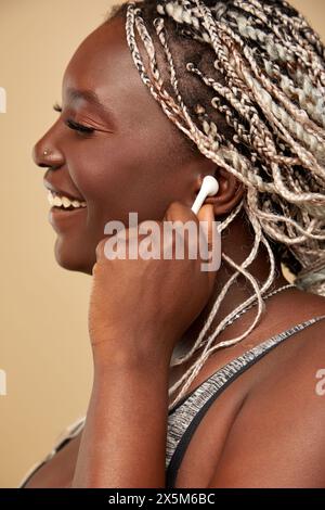 Profilo di donna sorridente che inserisce l'auricolare nell'orecchio Foto Stock