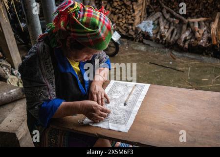 Una donna Flower Hmong disegna un modello per il suo ricamo tradizionale, Mu Cang Chai, Yen Bai, Vietnam Foto Stock