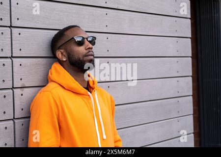 Regno Unito, South Yorkshire, uomo con cappuccio giallo appoggiato contro il muro Foto Stock