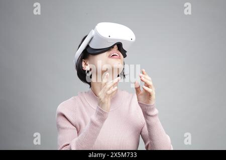 Giovane donna utilizzando la realtà virtuale auricolare Foto Stock