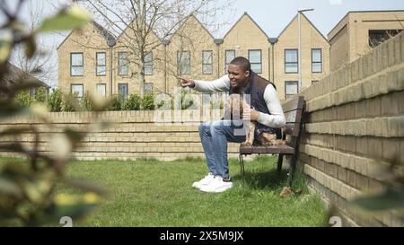 Uomo con cane seduto sulla panchina del parco Foto Stock