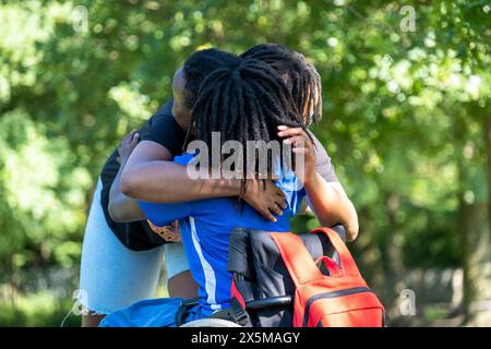 Adolescente (16-17) in sedia a rotelle incontro con un amico nel parco Foto Stock