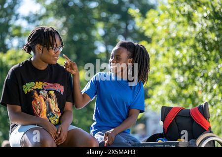 Adolescente (16-17) in sedia a rotelle con un amico nel parco Foto Stock