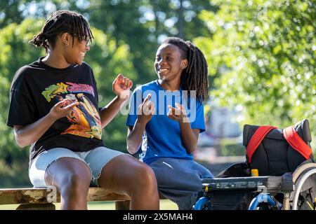 Adolescente (16-17) in sedia a rotelle con un amico nel parco Foto Stock