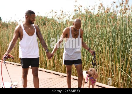 USA, Louisiana, coppia gay che cammina sul lungomare con cani Foto Stock