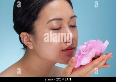 Ritratto in studio di una donna che puzza di peonia rosa Foto Stock