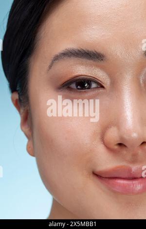 Primo piano del volto di una donna su sfondo blu Foto Stock