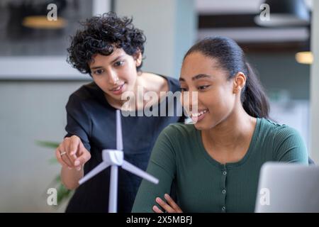 Giovani ingegneri che giocano con il modello di turbina eolica in ufficio Foto Stock