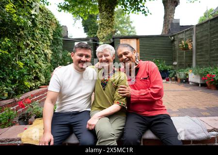Ritratto di una coppia senior sorridente con un figlio adulto nel cortile Foto Stock