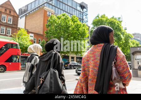Vista posteriore di giovani donne che indossano hijab che camminano in città Foto Stock