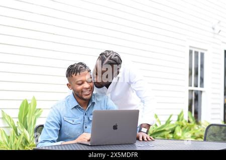 USA, Louisiana, coppia gay che guarda il laptop al tavolo del cortile Foto Stock