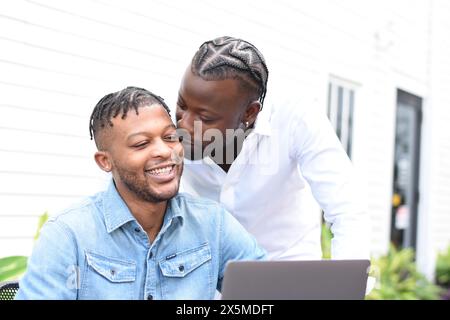 USA, Louisiana, uomo che bacia fidanzato usando un computer portatile al tavolo del cortile Foto Stock