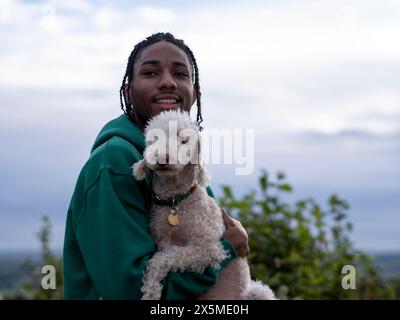 Ritratto di un adolescente (16-17) che tiene in mano un cane Foto Stock