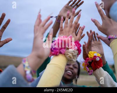 Gruppo di amici adolescenti (16-17) che mettono le mani in alto Foto Stock