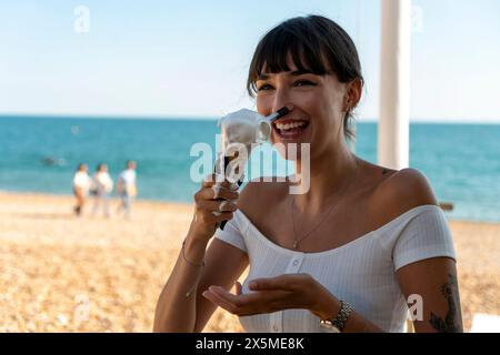 Donna sorridente che tiene in mano un gelato che scioglie Foto Stock