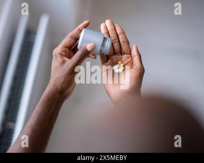 Primo piano di una persona che versa pillole a portata di mano Foto Stock