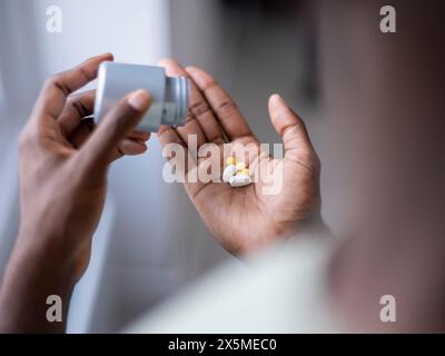 Primo piano di una persona che versa pillole a portata di mano Foto Stock