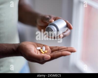 Primo piano di una persona che versa pillole a portata di mano Foto Stock