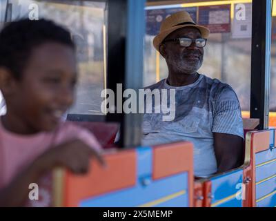 Uomo anziano con nipote (8-9) su un treno turistico terrestre Foto Stock