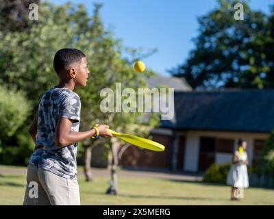 Ragazzo (10-11) che gioca a paddle ball in giardino Foto Stock