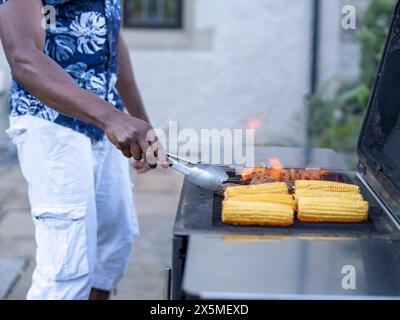 Uomo che grigia mais e carne alla griglia Foto Stock