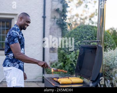 Uomo che grigia mais e carne alla griglia Foto Stock