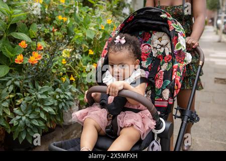 Madre che va a camminare con la figlia (12-17 mesi) nel passeggino Foto Stock