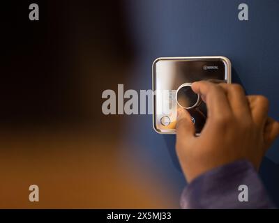 Uomo che usa il termostato a casa Foto Stock