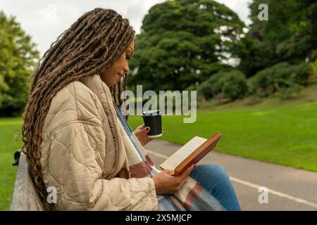 Donna in un libro di lettura cappotto in autunno Foto Stock