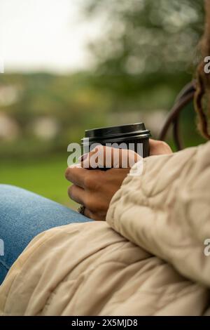 Primo piano delle mani di una donna che tiene all'aperto una tazza monouso Foto Stock