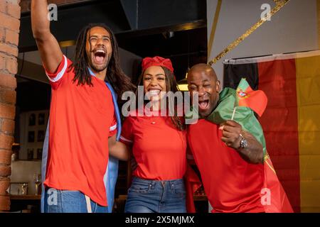 Amici vestiti con bandiere nazionali che celebrano la competizione di coppa del mondo Foto Stock