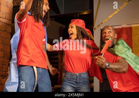 Amici vestiti con bandiere nazionali che celebrano la competizione di coppa del mondo Foto Stock