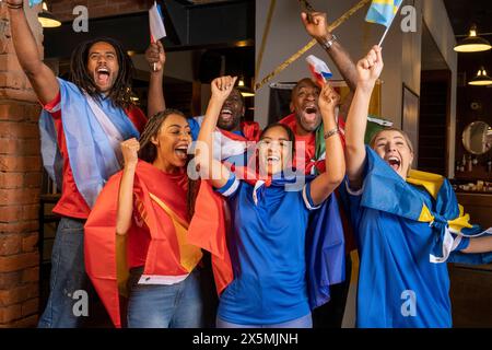 Amici vestiti con bandiere nazionali che celebrano la competizione di coppa del mondo Foto Stock