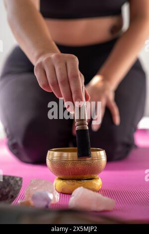 Primo piano di una donna con una ciotola da canto nello studio di yoga Foto Stock