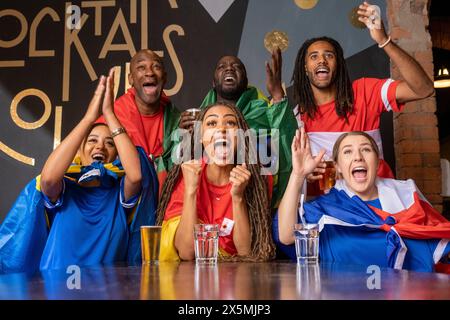 Amici vestiti con bandiere nazionali che celebrano la competizione di coppa del mondo Foto Stock