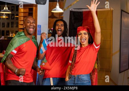 Amici vestiti con bandiere nazionali che celebrano la competizione di coppa del mondo Foto Stock