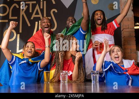 Amici vestiti con bandiere nazionali che celebrano la competizione di coppa del mondo Foto Stock