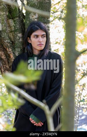 Ritratto di donna pensiva in piedi nella foresta Foto Stock