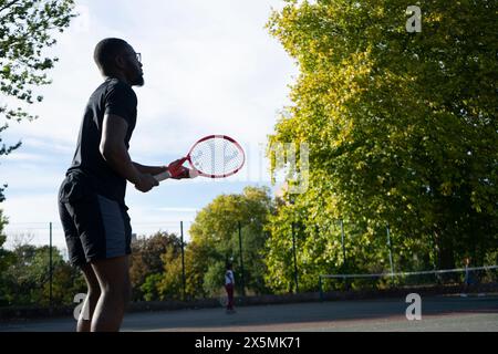 Uomo che gioca a tennis sul campo di quartiere Foto Stock